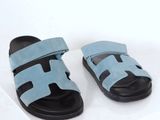 pair of light blue sandals with black soles on a white surface