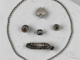 une photo d'un ensemble composé d'un collier et de boucles d'oreilles sur lequel est dessiné un visage triste