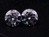 a pair of round cut diamonds on a black surface