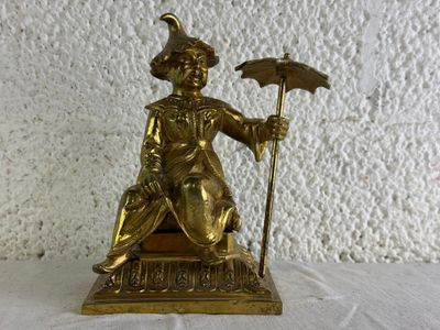 une statue en or représentant un homme tenant un parapluie