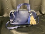 un sac à main bleu avec un pompon suspendu à la poignée