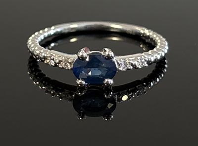 a close up of a ring with a blue sapphire and diamonds