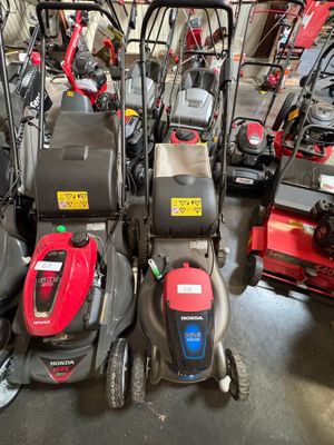 Plusieurs tondeuses à gazon sont alignées en rang dans un garage