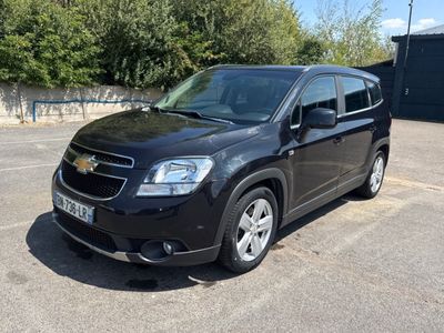 La voiture noire est garée sur le parking près des arbres.