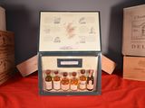 several bottles of alcohol are in a wooden box on a red cloth