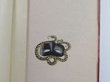 an open book with a picture of a mask and a snake on it