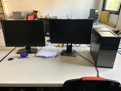 deux écrans d'ordinateur posés sur un bureau dans un bureau