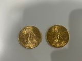 two gold coins sitting on top of a white table