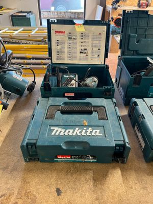 Trois outils Makita sont posés sur une table dans un atelier