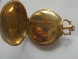 une montre de poche en or posée sur une table blanche
