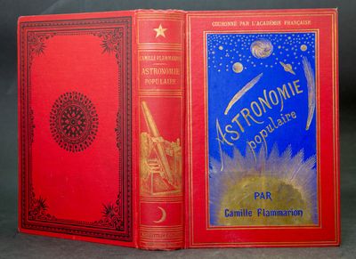 an old book with a red cover sitting on top of a table
