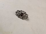 an old silver broochle with a red stone in it