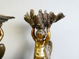 une statue représentant un garçon tenant un éventail, posée sur une table