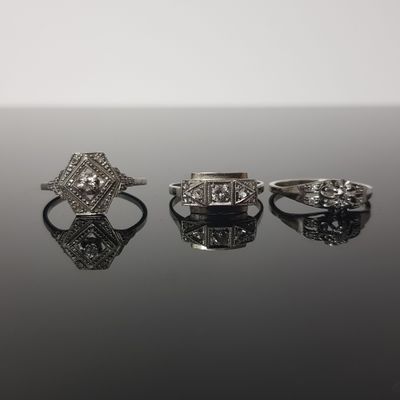 three diamond rings on a black surface with a white background