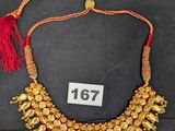 un gros plan sur un collier en or orné d'un pompon rouge