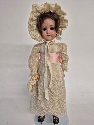 an old fashioned doll with a bonnet and dress on a white surface