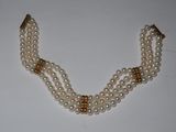 a close up of a necklace with pearls on a white surface