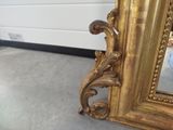 a gold mirror sitting on the floor next to a white wall