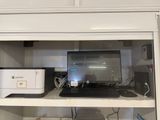 a computer and printer sitting on a shelf in a cabinet