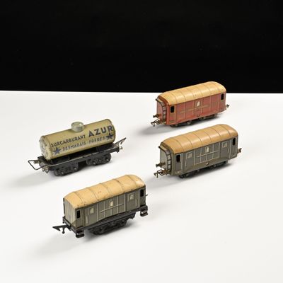 quatre wagons de train miniature sont alignés sur une surface blanche
