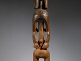 une statue en bois représentant un homme assis sur une table