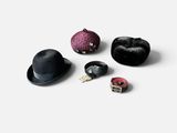 quatre chapeaux différents et une pince à chapeau posés sur une surface blanche