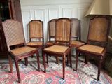 four wooden chairs with cane back and cane backs sit on a rug