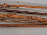 four wooden walking canes are lined up on a white surface