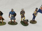 three figurines of men dressed in medieval clothing and holding flags