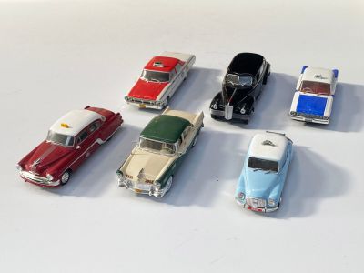 plusieurs petites voitures sont alignées sur une surface blanche