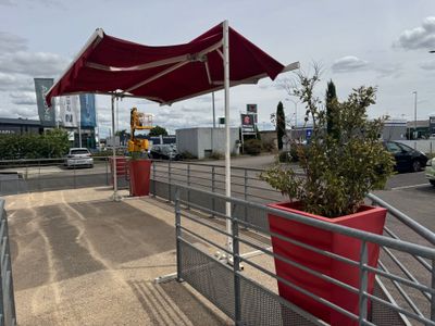 un parapluie rouge au-dessus d'une jardinière rouge au bord de la route