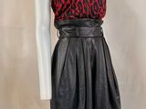 a mannequin wearing a red and black top and black leather skirt