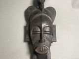 une image d'un masque en bois accroché au mur