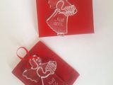 two red christmas ornaments with a little girl in a dress on them