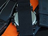 a close up of a watch on a black and orange strap