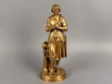 figurine en or représentant une femme avec un chien, sur fond blanc