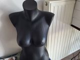 a black mannequin sitting on top of a table next to a lamp