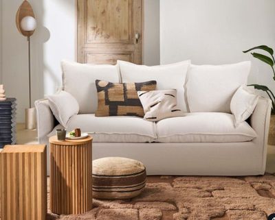 un salon avec un canapé blanc et un pouf marron