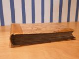 a brown book on a wooden table with blue and white striped wallpaper