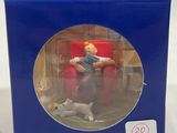 a toy figurine of a man sitting in a chair with a cat