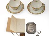 two tea cups and saucers with a book and a pocket watch
