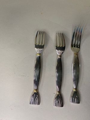 trois fourchettes et un couteau sur une table blanche
