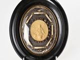 a gold coin in a black case on a white surface