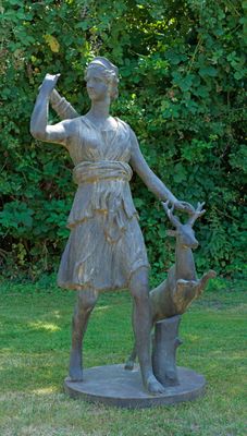 une statue représentant une femme et un chien dans l'herbe