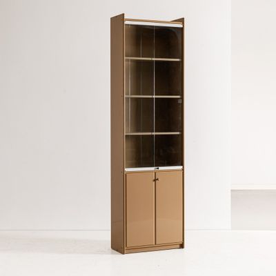 une grande armoire en bois avec une porte vitrée, dans une pièce blanche