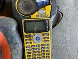 a yellow and black calculator sitting on the ground next to a tire