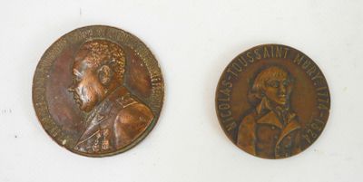 two bronze medallions of a man and a woman on a white surface