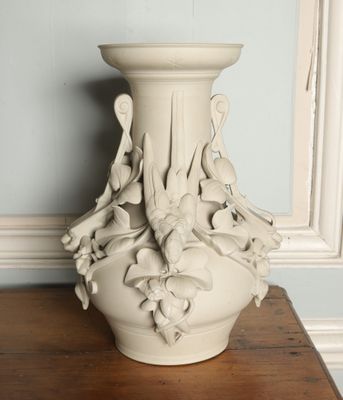 a white vase sitting on a table in front of a blue wall