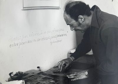 photographie en noir et blanc d'un homme travaillant sur un morceau de bois