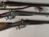 several old guns are lined up on a wall in a room
